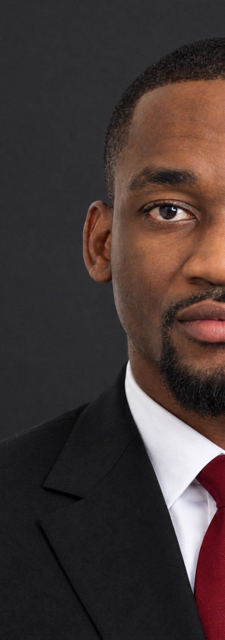 Half of Christian Katshunga's face, black suit and red tie