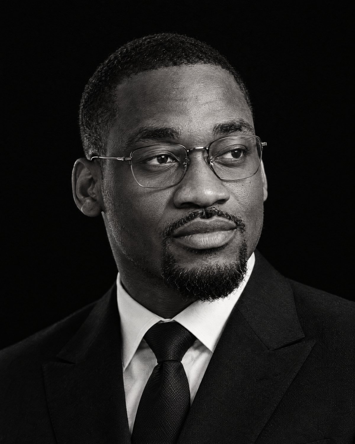 Black-and-white portrait of Christian Katshunga, glasses and dark suit